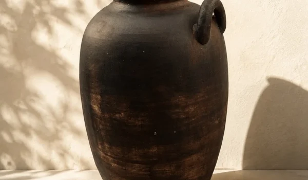 کوزه ی سفالی تک دسته مدرن دکوراتیو با پتینه قهوه‌ای سوخته روی میز چوبی عنوان تصویر: کوزه ی سفالی تک دسته مدرن